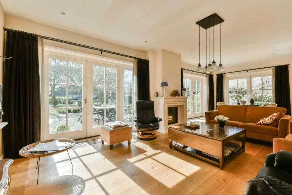 A sun-drenched 2026 living room in Southern California featuring an orange sofa, fireplace, and large glass doors, showcasing the professional results of Dana Point Building Expertise.