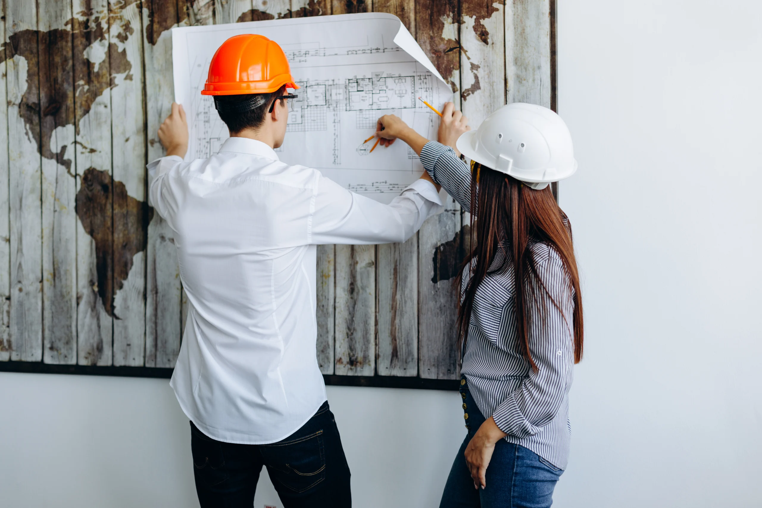 A group of professional architects and project managers in a well-lit office reviewing a detailed 2026 house floor plan, illustrating Our Remodeling Process: Simple, Clear, and Stress Free.