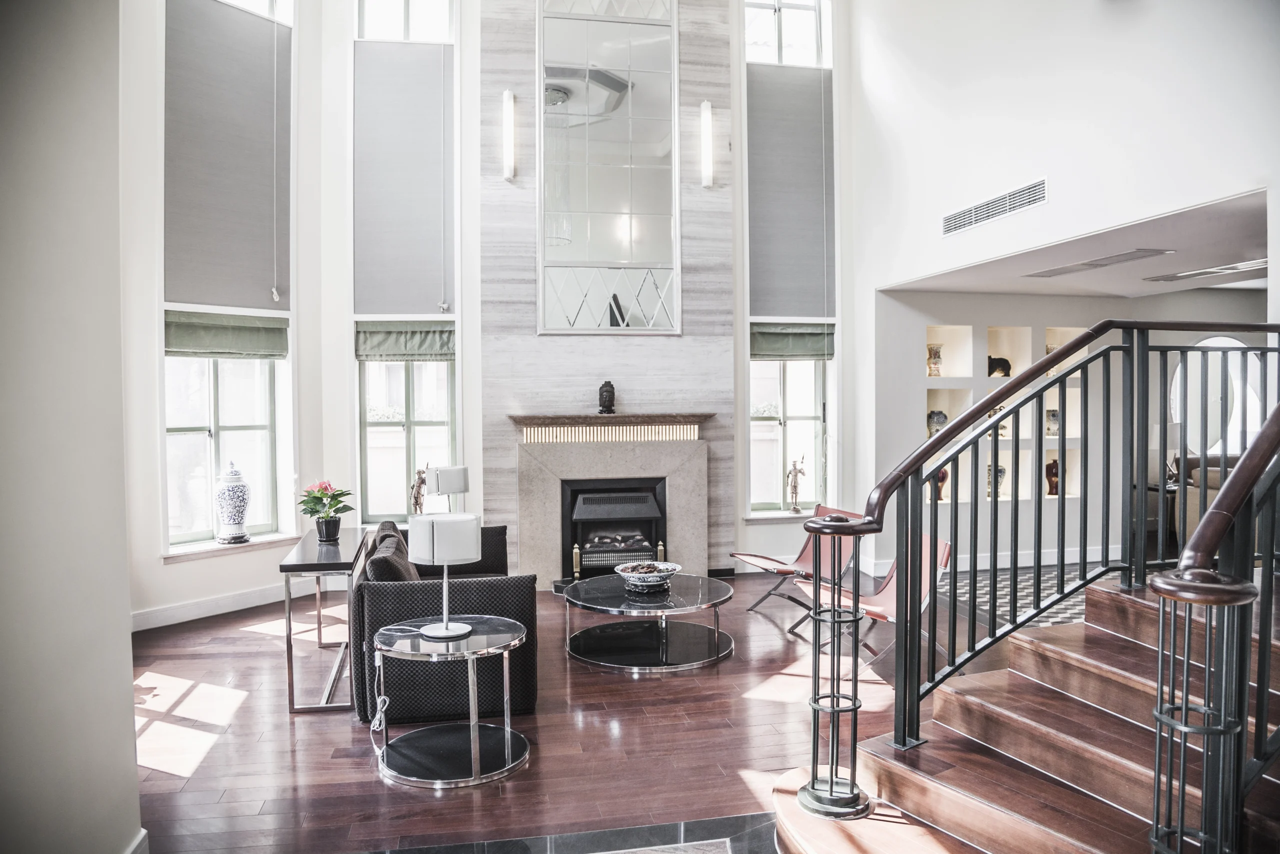 A bright and airy luxury living room with high ceilings, a grand fireplace, and a contemporary staircase, illustrating Why San Marcos Families Choose Poseidon Remodeling for their 2026 home transformations.