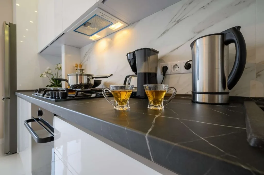 Close-up view of a modern kitchen featuring what is soapstone countertops with a dark stone surface, subtle white veining, and a marble backsplash.