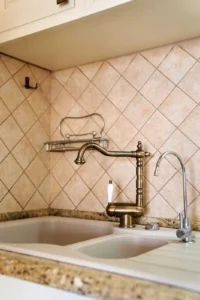 What is a pot filler, wall mounted pot filler faucet installed above a kitchen sink with tiled backsplash