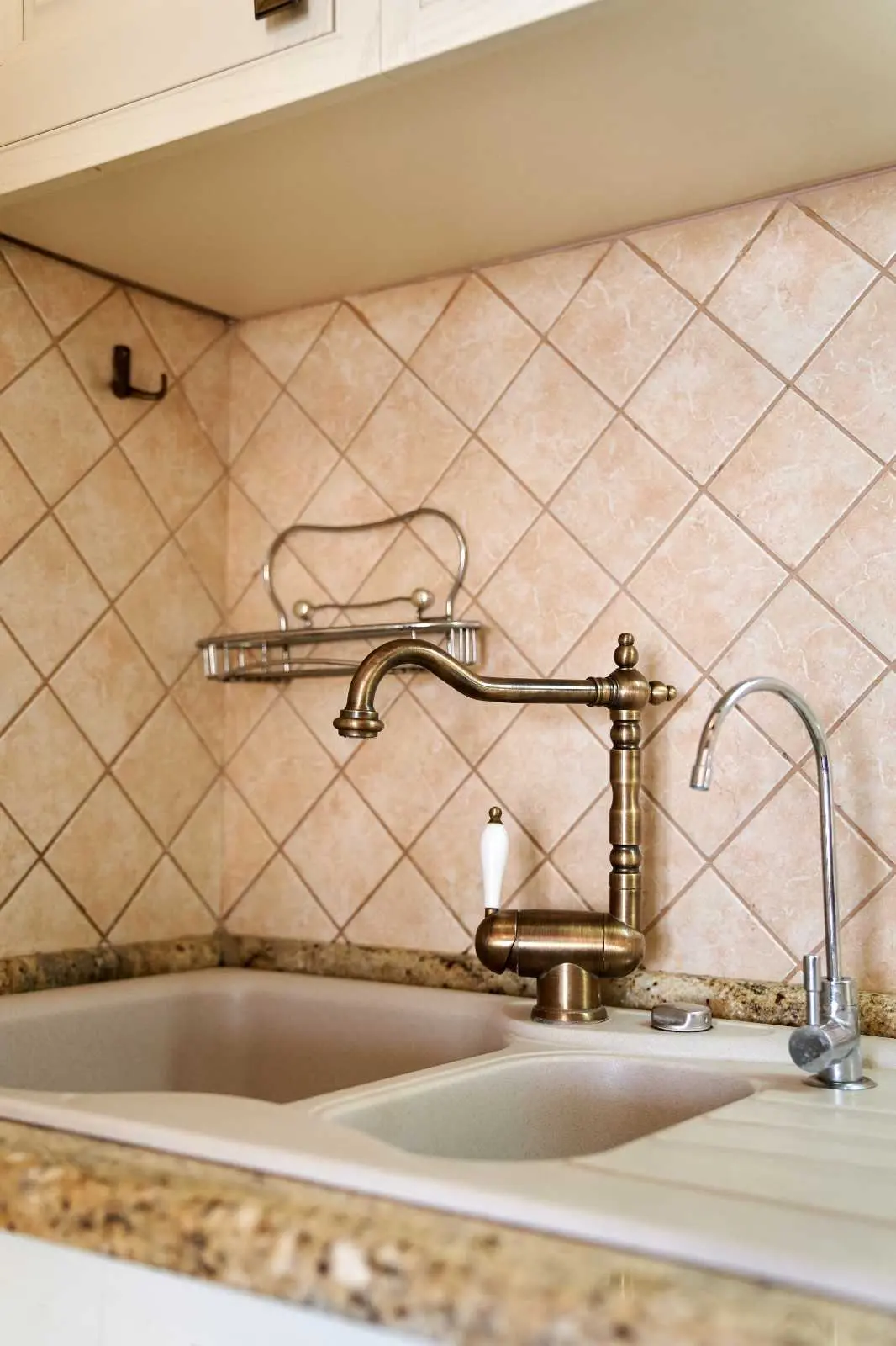 What is a pot filler, wall mounted pot filler faucet installed above a kitchen sink with tiled backsplash